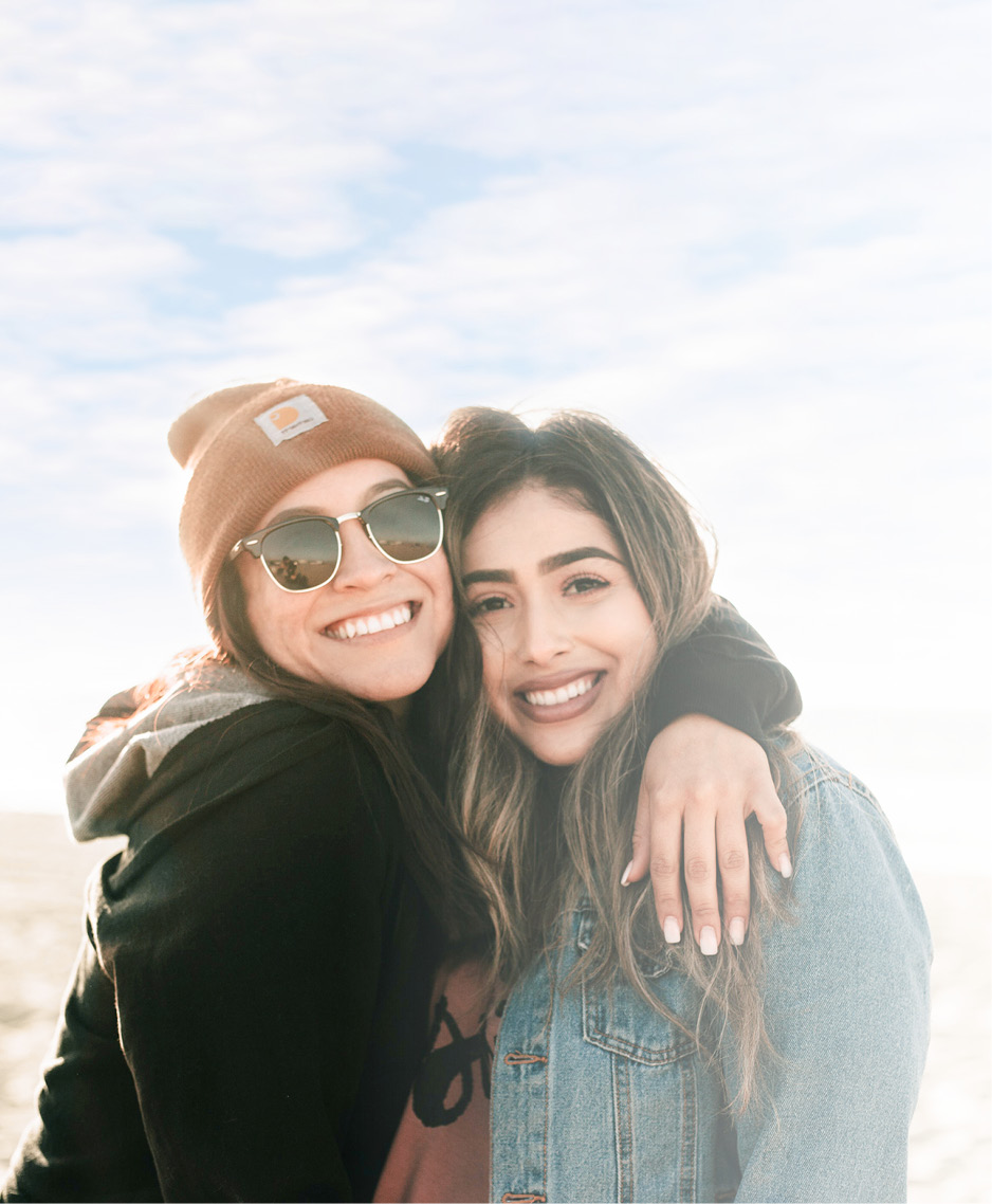 Zwei Freundinnen umarmen sich und schauen lächelnd in die Kamera: LTS bietet Verlässlichkeit und Respekt.
