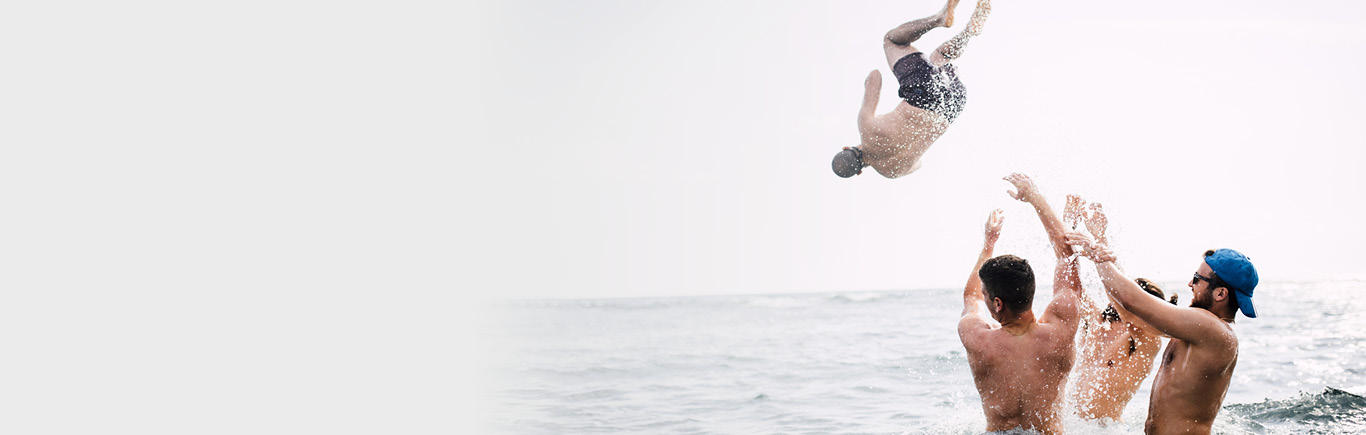 Drei Männer stehen hüfttief im Meer werfen einen vierten Mann ins Wasser: Dein Weg. Deine Zukunft. Dein LTS. Karriere bei LTS Lohmann Therapie-Systeme.