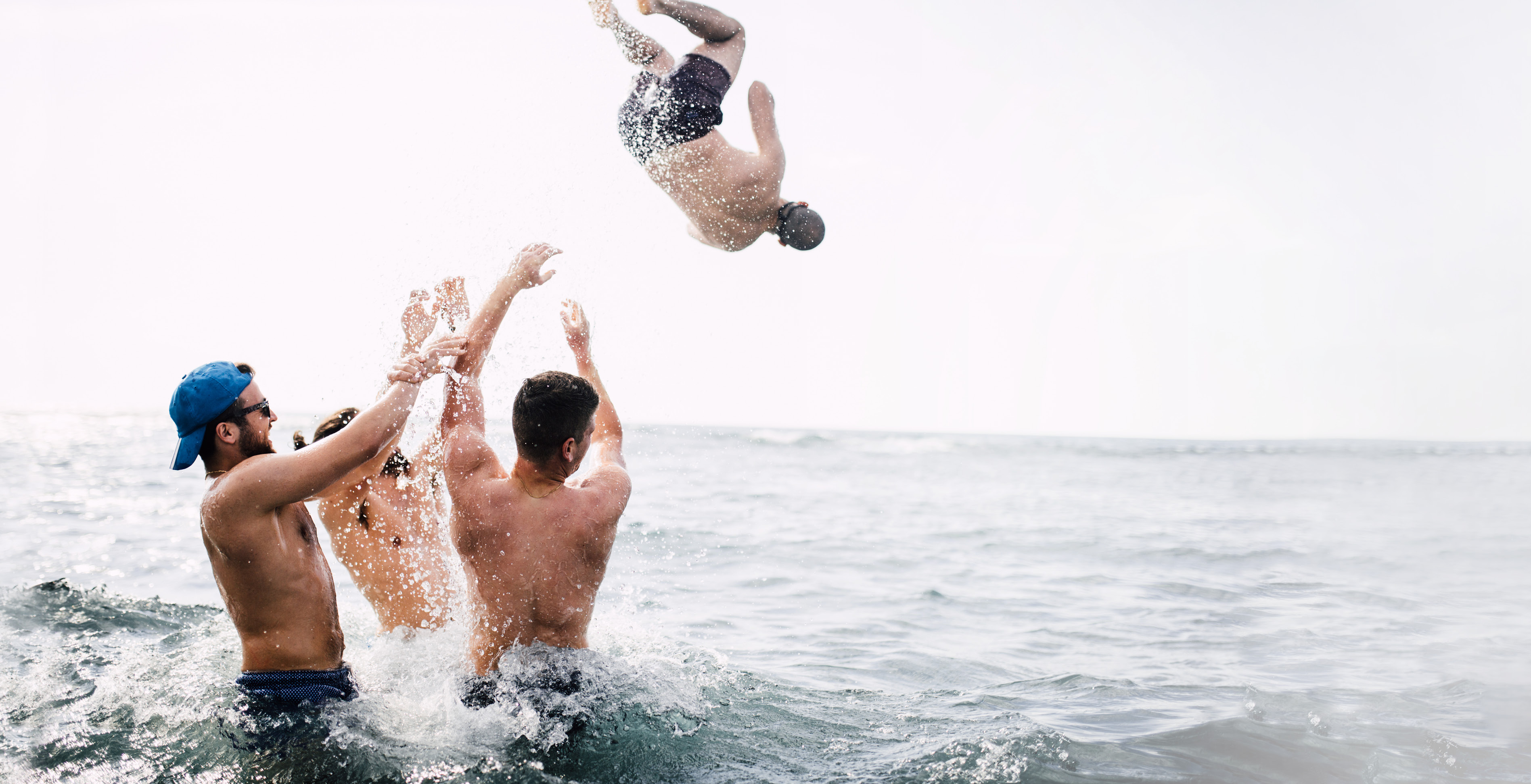 Drei Männer stehen hüfttief im Meer werfen einen vierten Mann ins Wasser: Dein Weg. Deine Zukunft. Dein LTS. Karriere bei LTS Lohmann Therapie-Systeme.