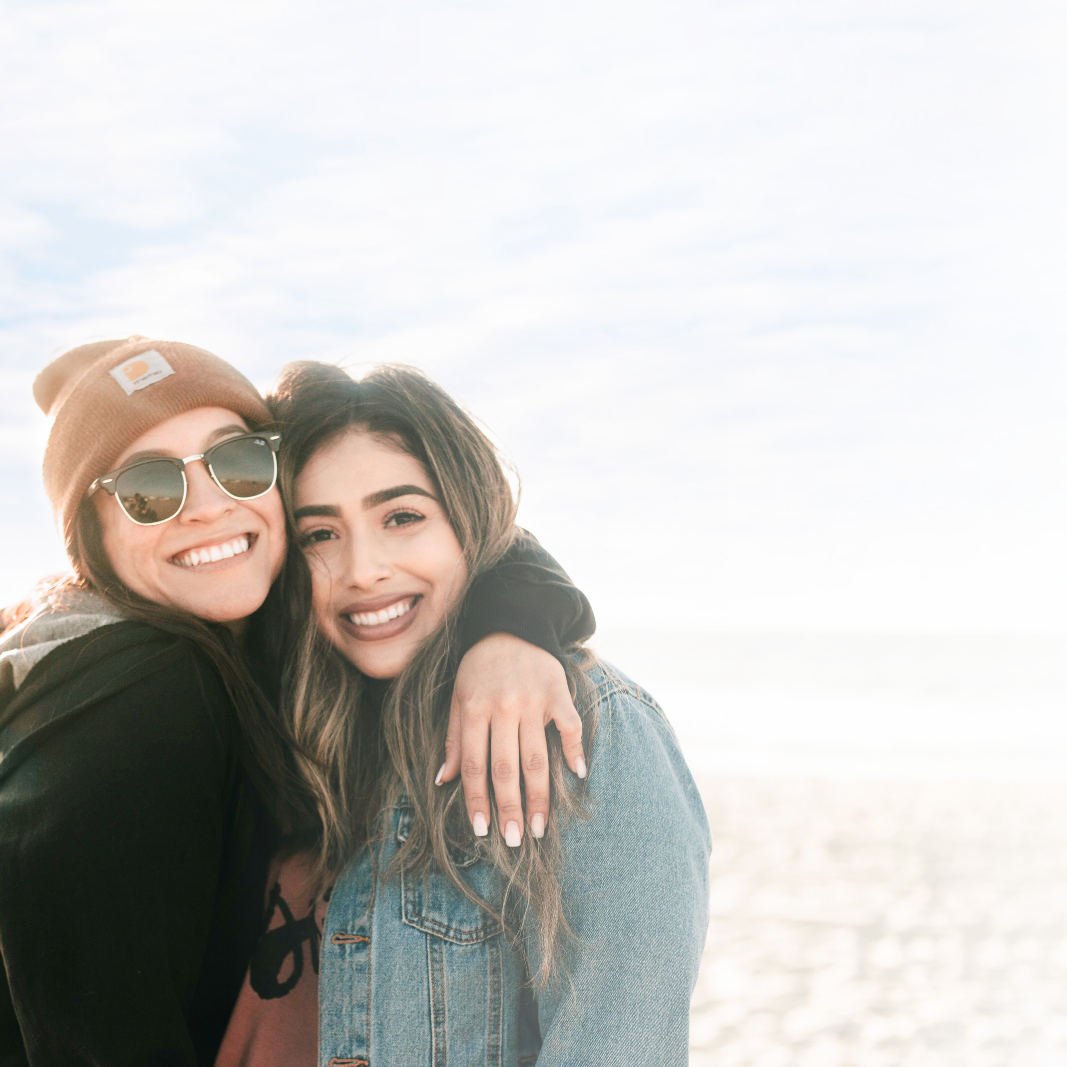 Zwei Freundinnen umarmen sich und schauen lächelnd in die Kamera: LTS bietet Verlässlichkeit und Respekt.