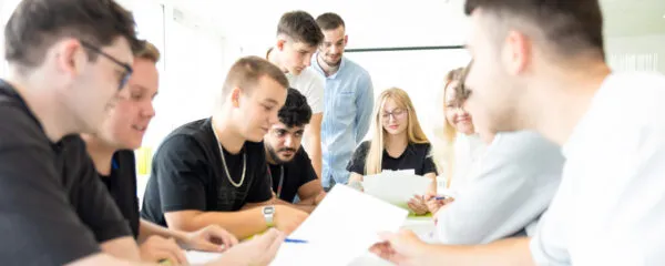 schueller-lts Mehrere Schüler:innen arbeiten gemeinsam an einem Tisch mit Unterlagen.